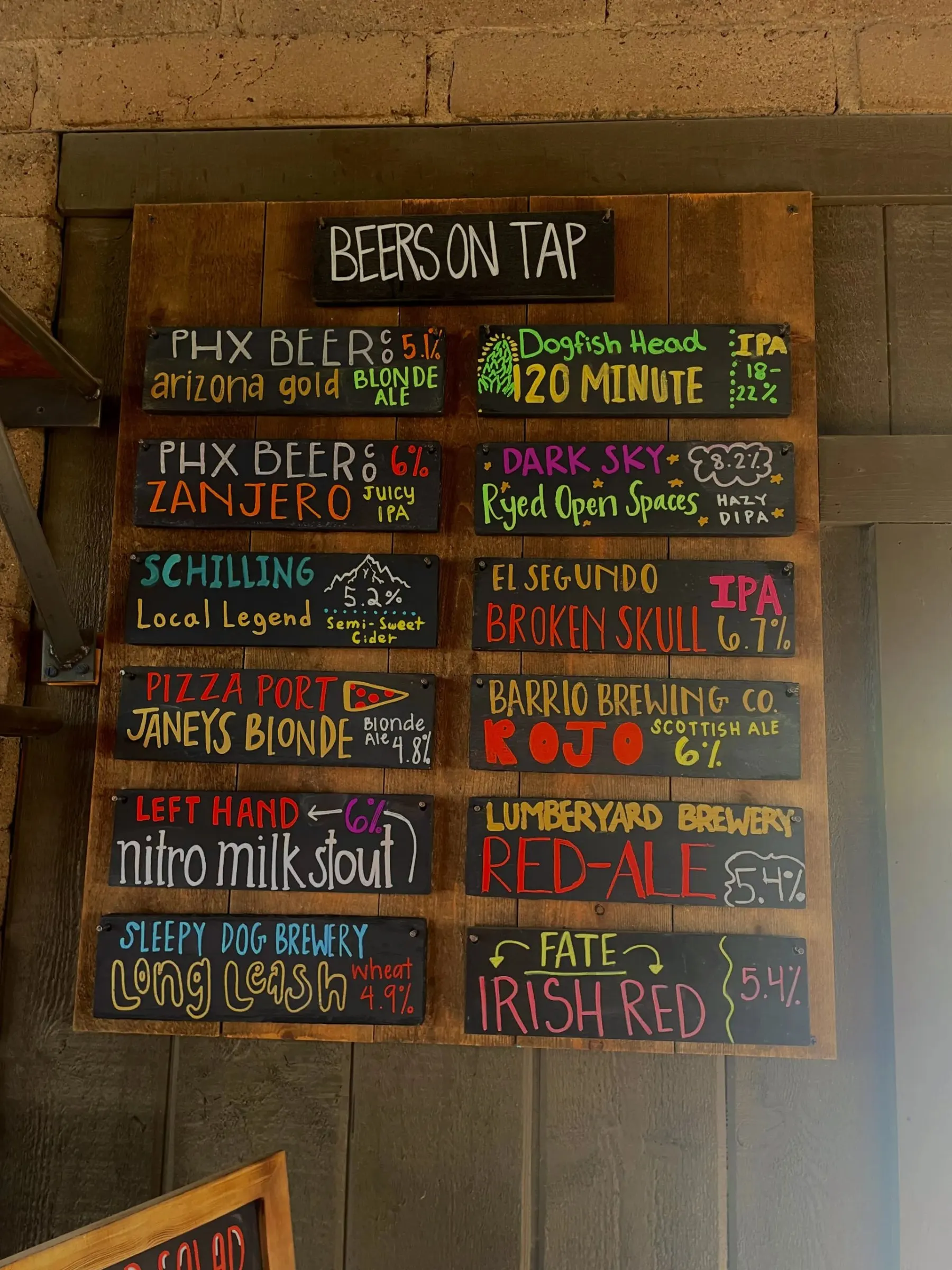 Colorful handwritten brewery and beer signs on Janey’s wooden tap board