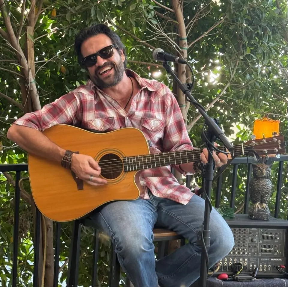 Dan Emrey smiling and playing his guitar.